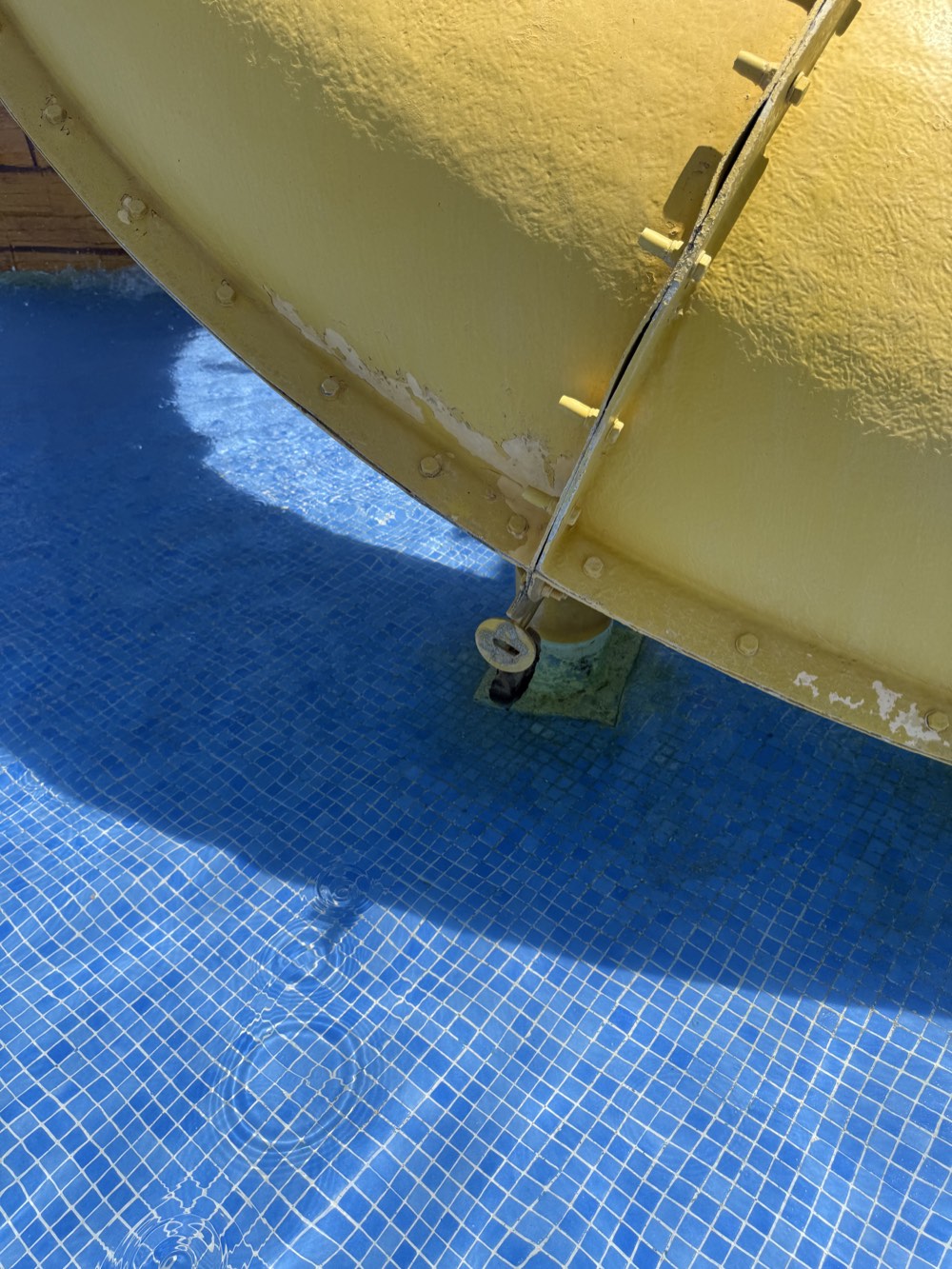 Open-looking seam and worn coating at the joint of the yellow slide.